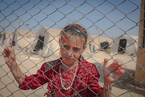 Refugee girl behind fence.