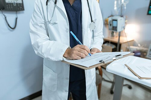 Picture of person in white Doctors coat with pen and clipboard
